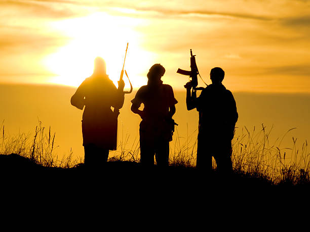 Silhouettes of soldiers against a sunset stock photo