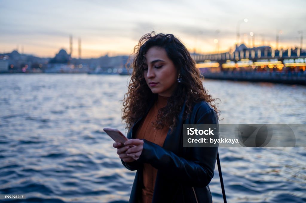 woman with curly hair writing message with phone Adult Stock Photo woman with curly hair writing message with phone Adult Stock Photo