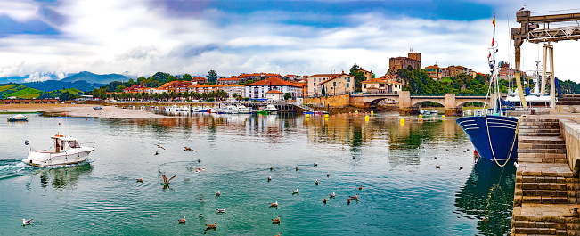 Scenic medieval village ,mountain and sea panoramic landscape in northern Spain.Green meadows and boats in the port