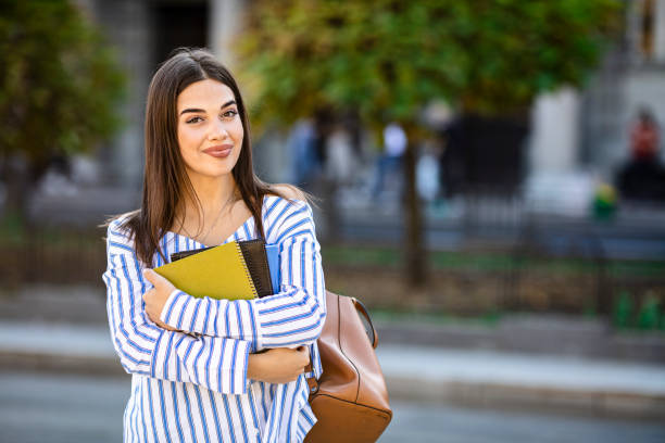 istock Young female student with folders and backpack in college campus. 1199299097