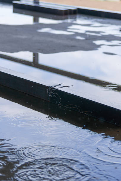 istock Big square metal pipes parts under rain on construction with sky in reflection. 1199299652