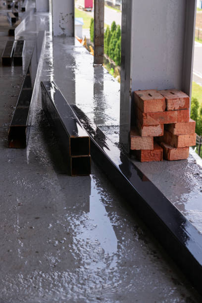 istock Big square metal pipes parts under rain on construction with sky in reflection. 1199299675
