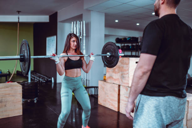 istock Female And Her Instructor Working On Her Barbell Lifting Form In Gym 1199306200