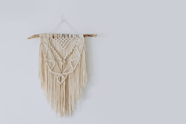 Handmade macrame decoration hanging on a white empty wall. Handmade stylish cotton macrame decoration hanging on a white empty wall. Copy space. tapestry photos stock pictures, royalty-free photos & images