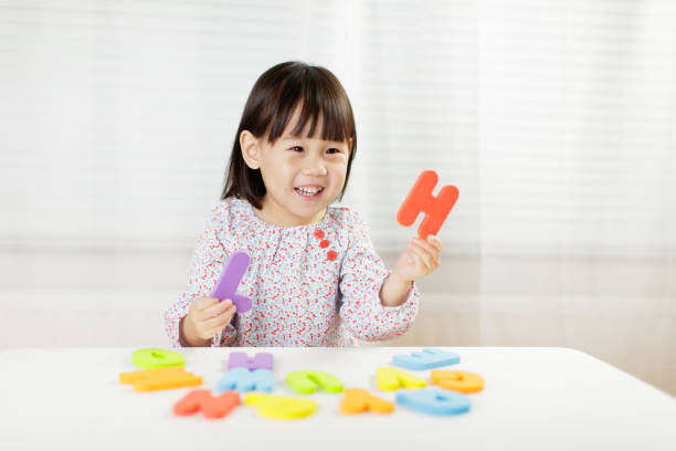 kleinkind mädchen lernen alphabet buchstaben zu hause vor weißem hintergrund - english game stock-fotos und bilder