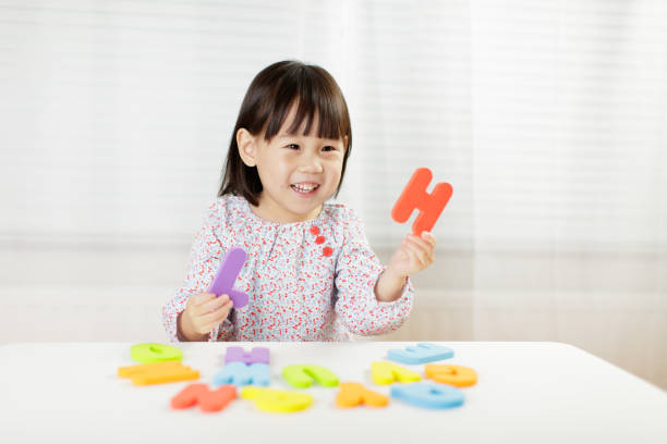 白い背景に対して自宅でアルファベット文字を学ぶ幼児の女の子 - preschooler ストックフォトと画像