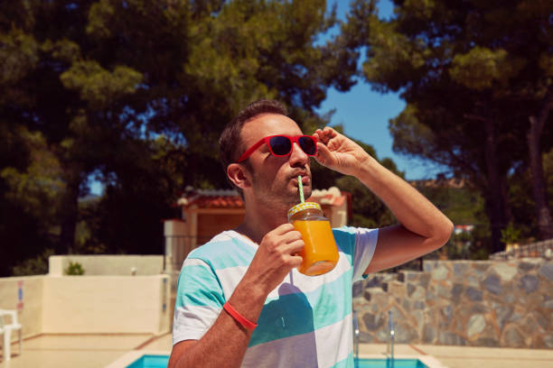 istock Attractive man drinking juice on the swimming pool. Summer concept. 1199316526