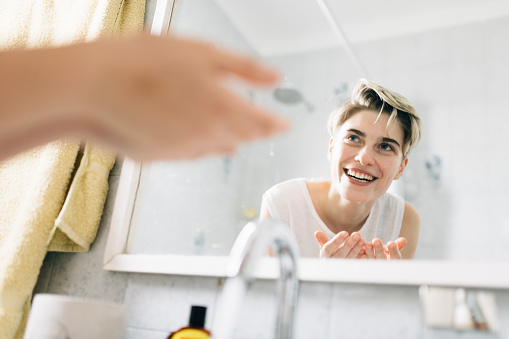 Young woman washing face on bathroom sink