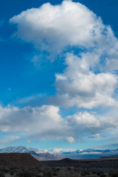istock billowy white clouds in blue sky above mountain valley 1199319962