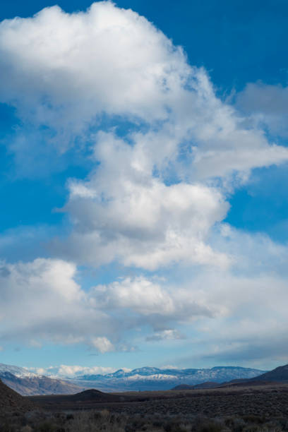 istock billowy white clouds in blue sky above mountain valley 1199319963