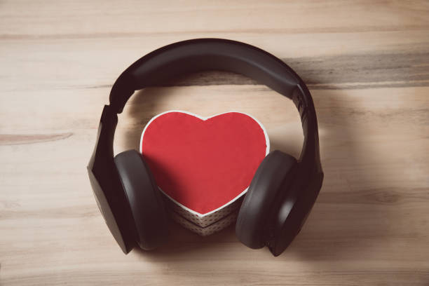 istock Full-size wireless headphones pulled over small red heart-shaped box on a light brown wooden table. Love music concept 1199326851