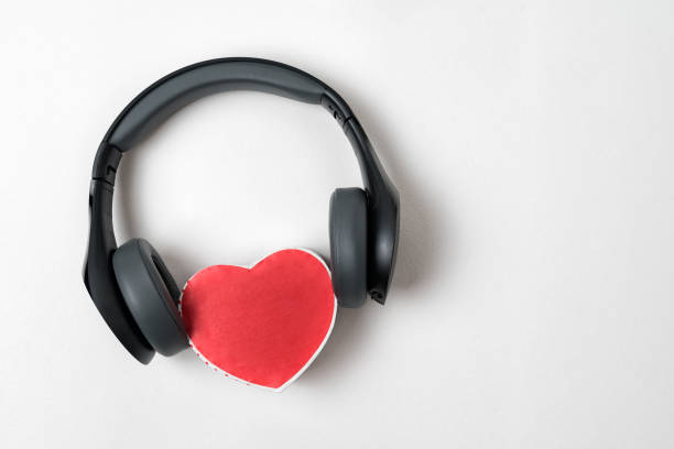 istock Full-size wireless headphones pulled over small red heart-shaped box on white table. Love music concept. Directly above 1199326905