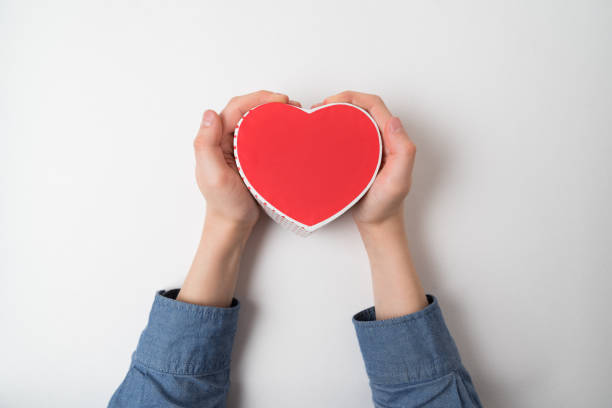 istock Small red heart shaped box in male hand isolated on white background 1199326937