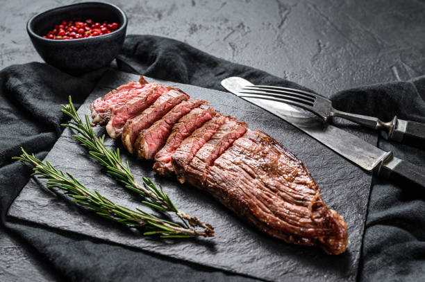 istock Steak of marbled beef roasting medium on a black stone Board. Black background. Top view 1199328311
