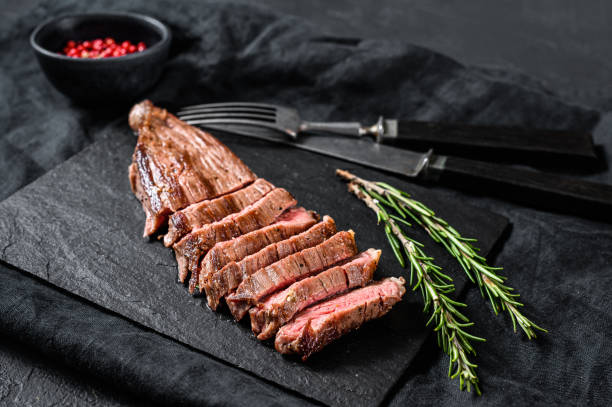 istock Roasted medium rare sliced flank beef steak. Black background. Top view 1199328488