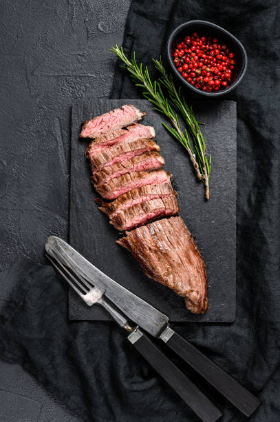 istock Roasted medium rare sliced flank beef steak. Black background. Top view 1199328586