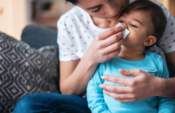 Mother helping her baby son to blow his nose Mother helping her baby son to blow his nose cold virus stock pictures, royalty-free photos & images