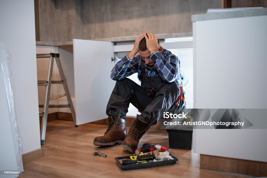 worried manual worker at construction site. Worried manual worker at construction site, carpenter worried in fitting new kitchen. Carpenter Stock Photo