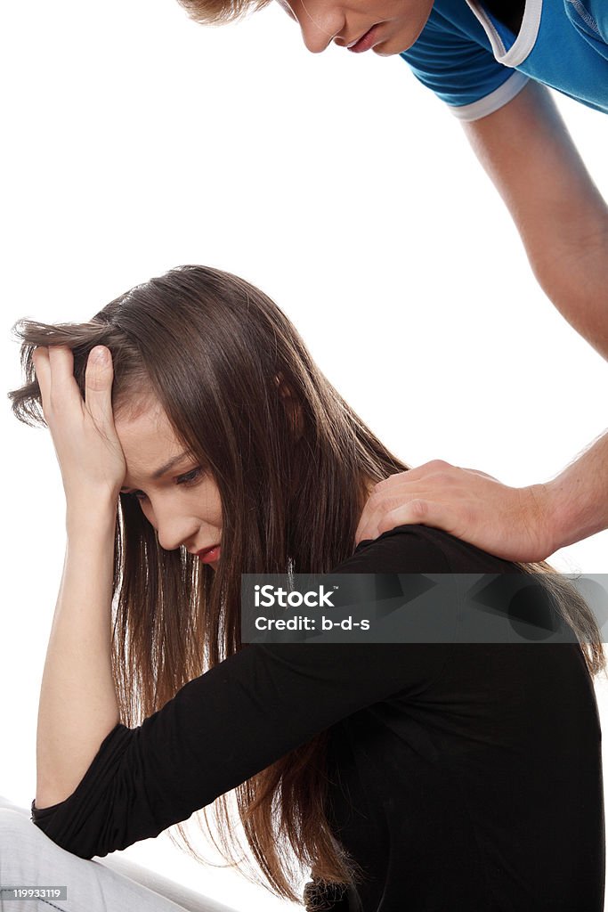 Depression and Sorrow Dark haired depressed young woman who is supported by her partner who's hand is touching her hand on her her shoulder. Isolated on white. 20-24 Years Stock Photo
