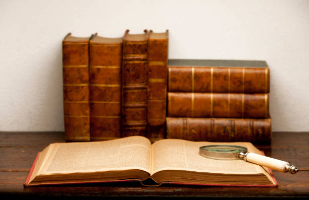 istock open old book, with retro old magnifying glass on wooden table and white background 1199331290