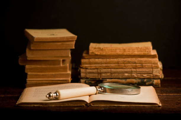 open old book, with retro old magnifying glass on wooden table and dark background