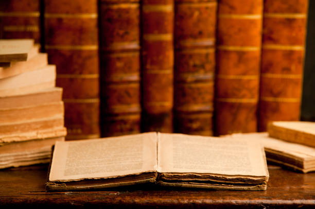 istock open old book with stack of old retro books on old wooden table and dark background 1199331446