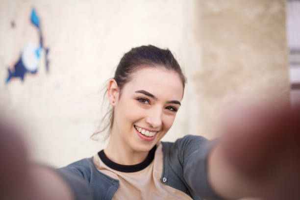 istock happy young woman taking selfie against wall 1199331616