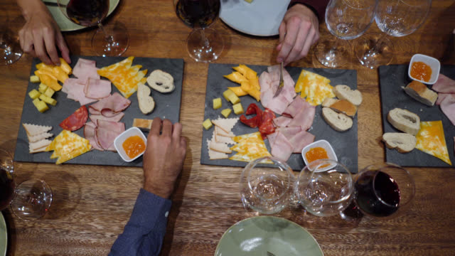 Unrecognizable group of friends enjoying cheese and ham during a wine tasting