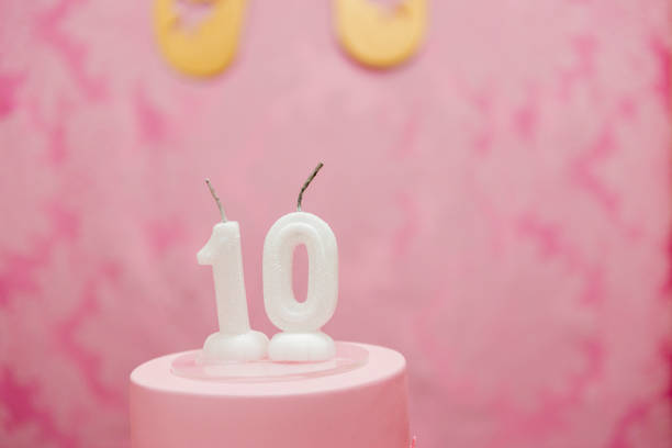 istock Birthday cake with candles as number ten on pink arabesques background. 1199332977