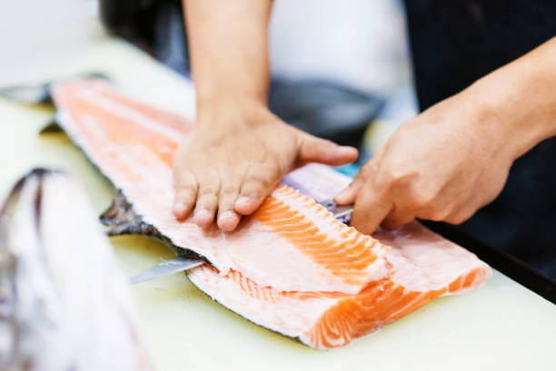 istock Chef cutting fresh salmon fillet in kitchen, chef cuts the salmon 1199335302