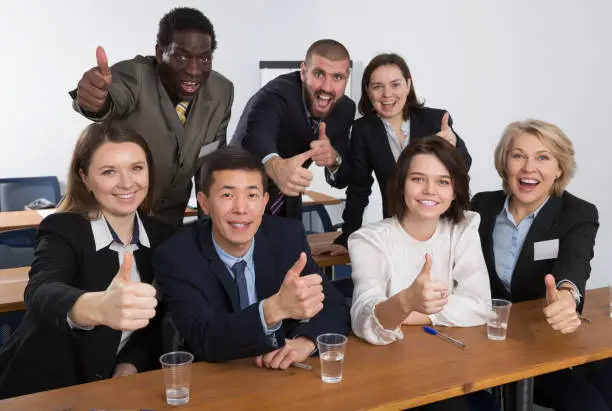 smiling international team of business people emotionally gesturing and celebrating in boardroom