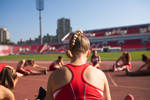 Young athletics team on a sports stadium, stretching before training