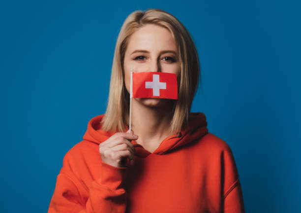 girl holds Switzerland flag on blue background stock photo