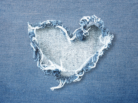 Heart shape ripped jean denim texture for Valentine's card background. Love concept.