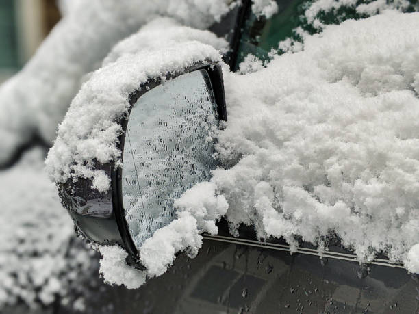 foco seletivo em um espelho traseiro gelado, coberto neve do carro durante uma tempestade de neve - car winter road reflector snow - fotografias e filmes do acervo