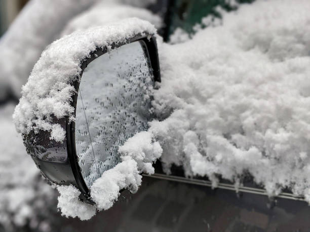 foco seletivo em um espelho traseiro gelado, coberto neve do carro durante uma tempestade de neve - car winter road reflector snow - fotografias e filmes do acervo