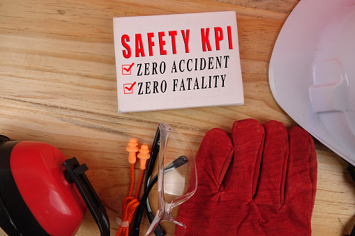 HEALTH AND SAFETY CONCEPT. Personal protective equipment on wooden table background with SAFETY KPI, ZERO ACCIDENT, ZERO FATALITY text.