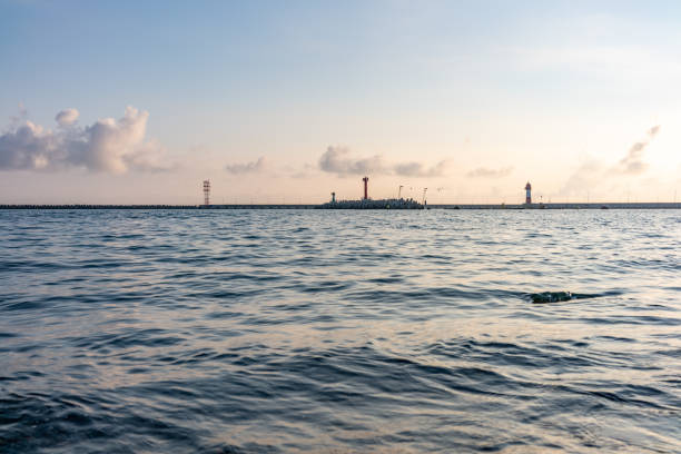 istock Sea harbor with breakwater and lighthouse at sunset. 1199347947