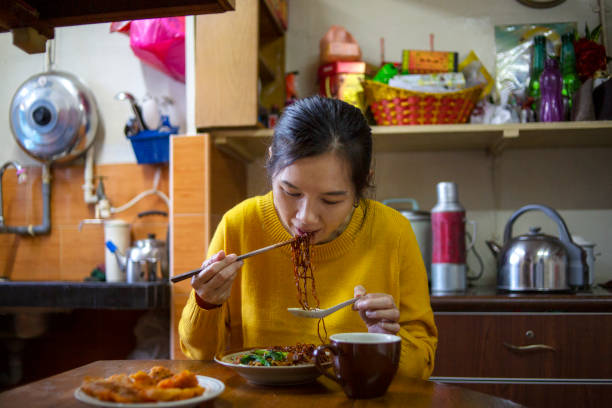 istock Asian woman eating noddle using chopsticks at home 1199350311