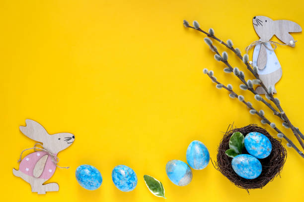 istock Easter greeting card with blue easter eggs and easter bunny on yellow background. Top view with space for your text. 1199351157