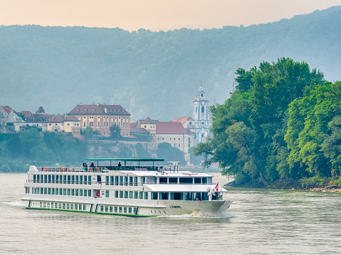 The Austrian region of the Danube River Valley on May 27, 2018: View of the Danube River with the town of Durnstein and a passing river cruise boat in Austria
