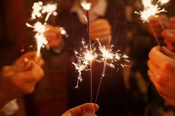 family celebrating christmas holidays, party people holding sparklers, festive lights for new year or birthday