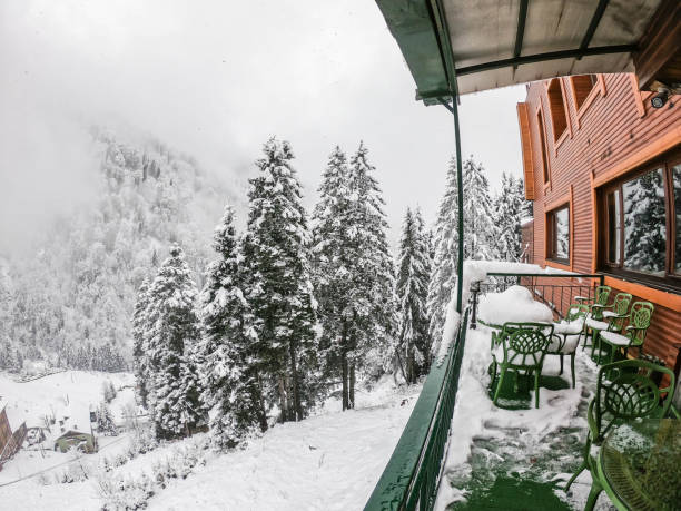 green table and chair at hotel terrace with snow fall on pine tree in Ayder stock photo
