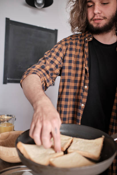 istock Young man with long hair cooks something in the kitchen. 1199370144