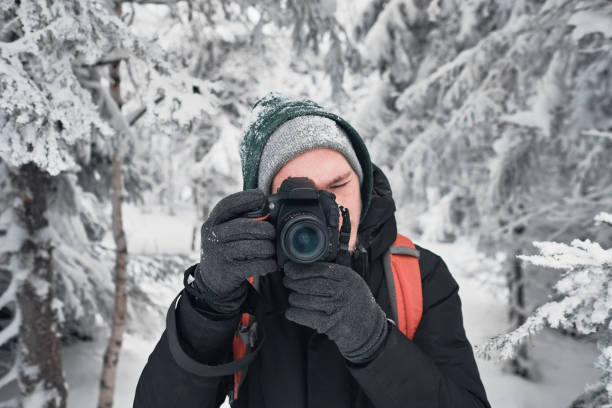 istock Photographer with frozen camera in winter forest 1199371585