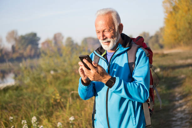 istock Senior man hiking using smart phone 1199376543