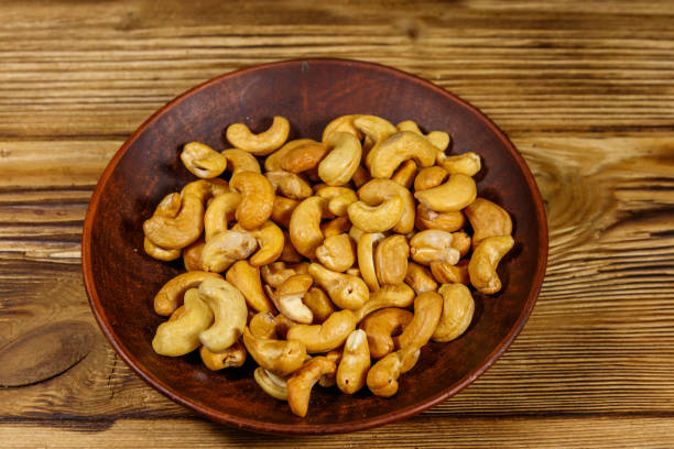 istock Ceramic plate with roasted cashew nuts on a wooden table 1199376638