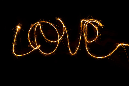 Fiery word Love from bengal lights at night. Inscription sparklers Love  on dark background. Happy Valentine day concept.