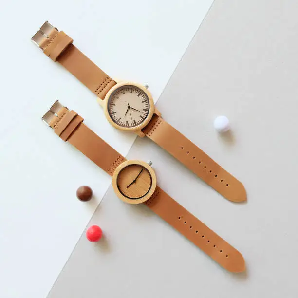 Photo of Top view of 2 wooden watches on white and brown color background.