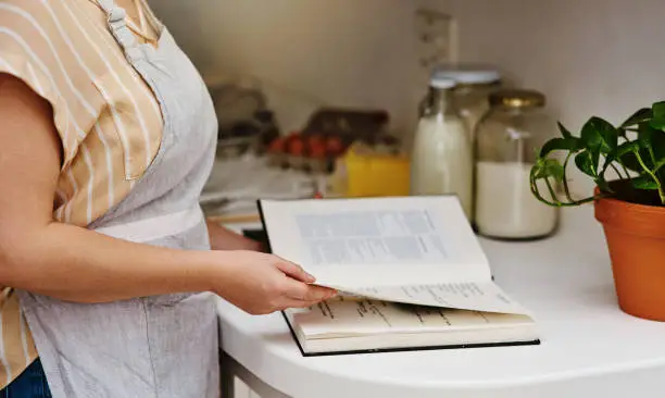 Cropped shot of an unrecognizable woman going through her recipe book